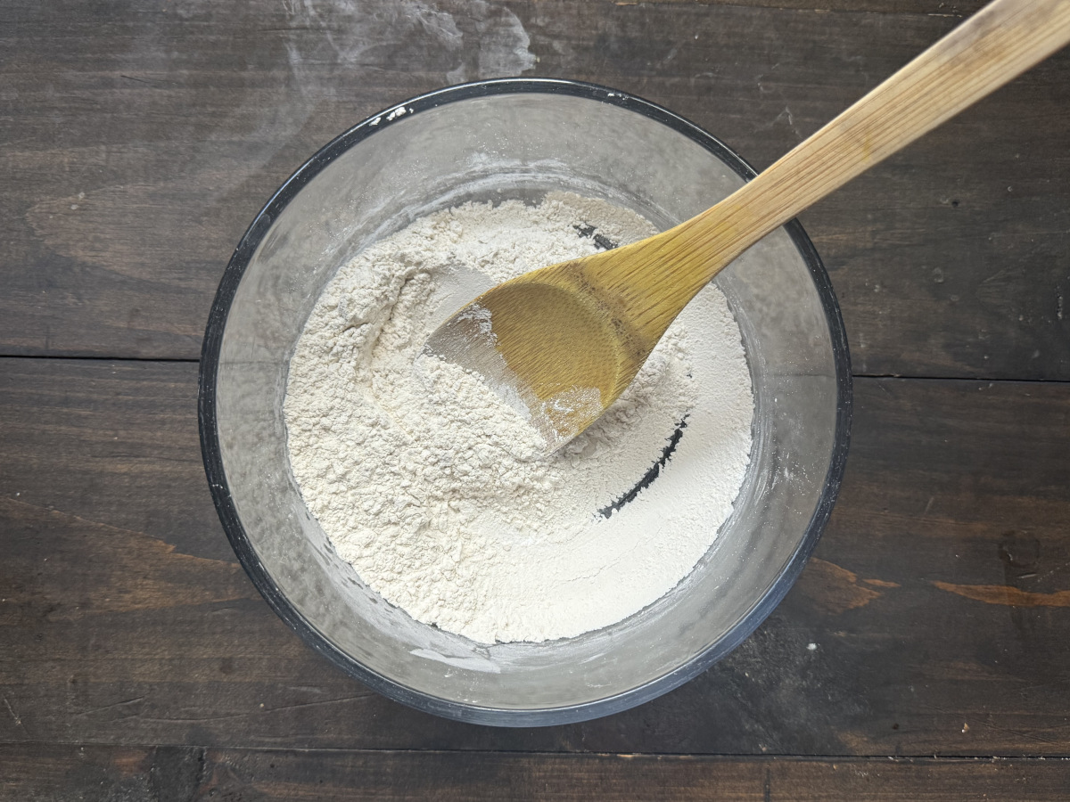 The dry ingredients mixed in a bowl with a wooden spoon.