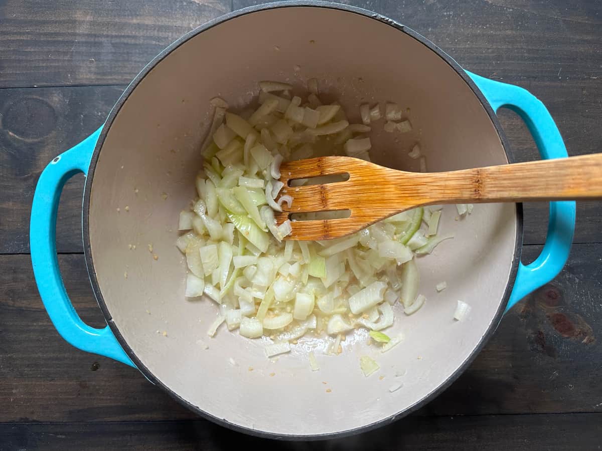 A pan with the onion and garlic sautéing inside.