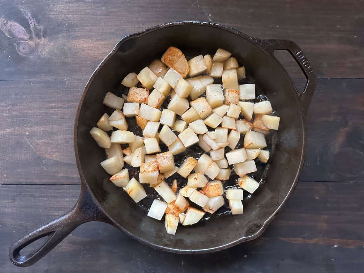 The potatoes cooking in a skillet.
