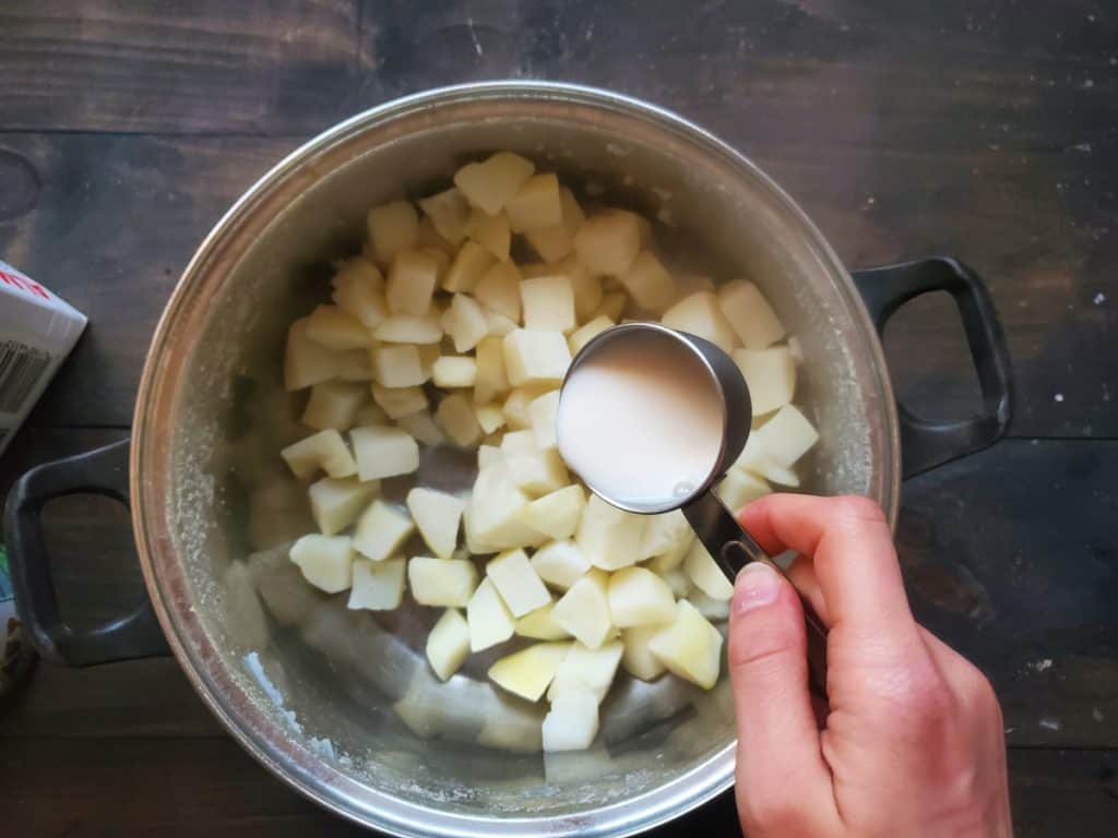 Adding the milk to the potatoes.