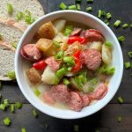 a bowl of kielbasa soup with bread
