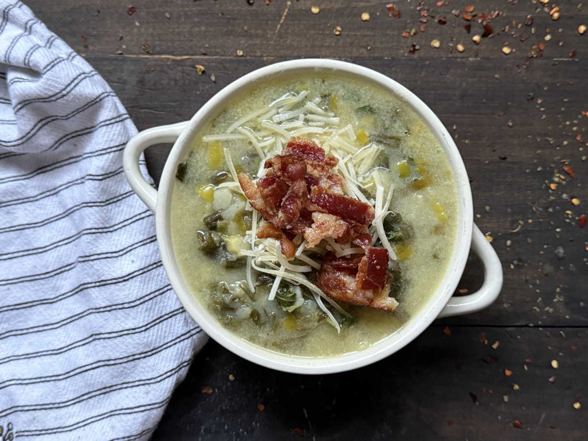 A bowl of potato leek and bacon soup, topped with bacon and parmesan.