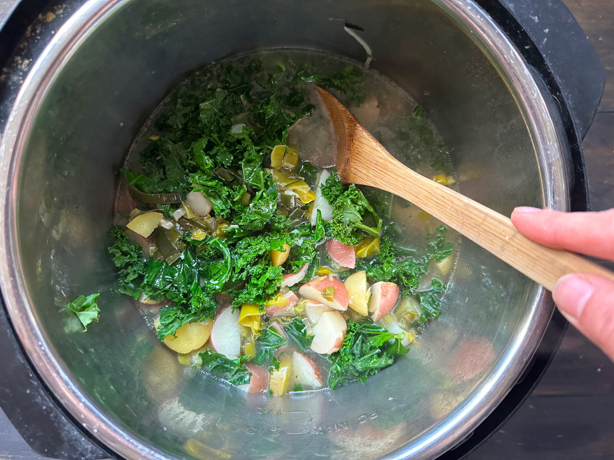 Stirring the greens into the soup.