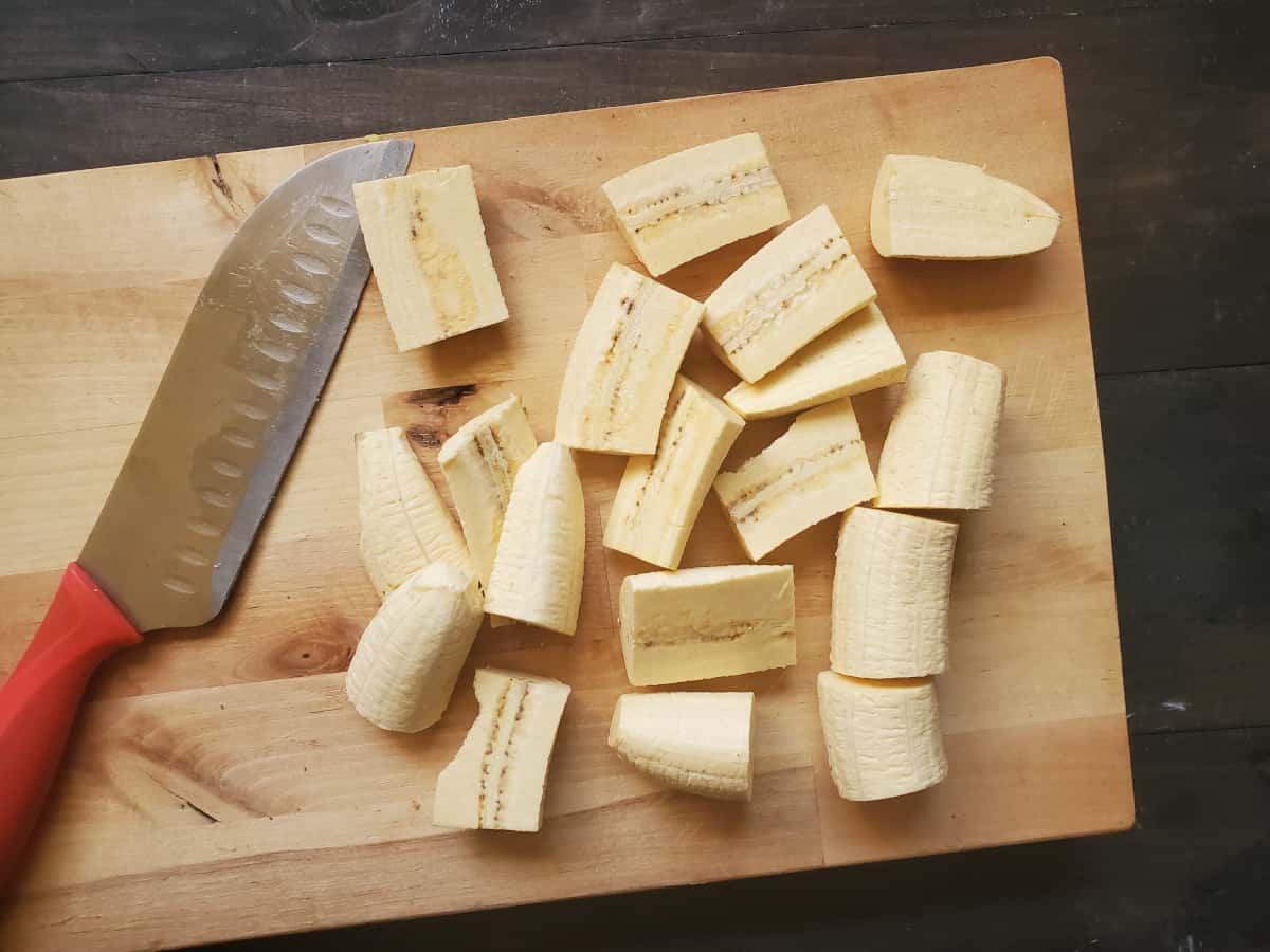Chopped plantains on a cutting board with a knife.