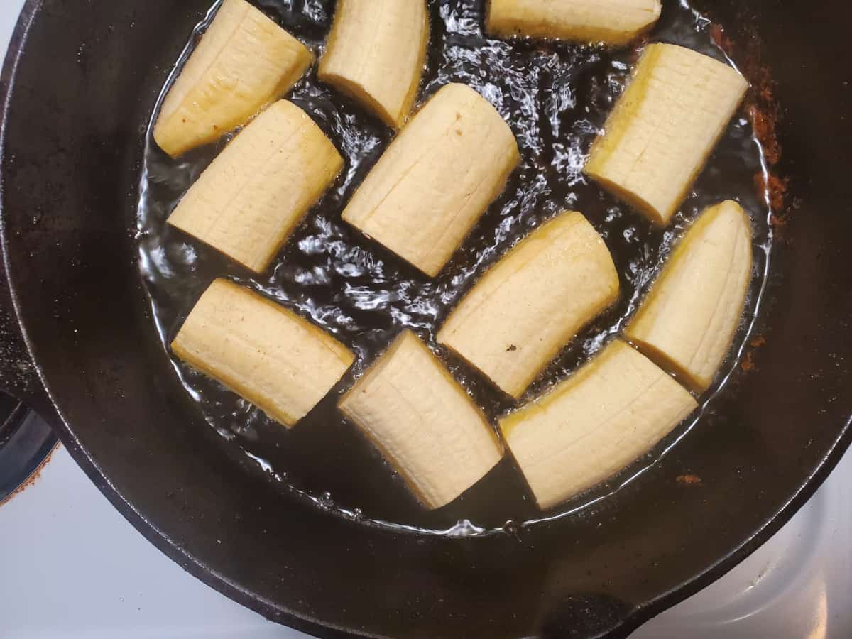 The plantain chunks frying in a skillet.