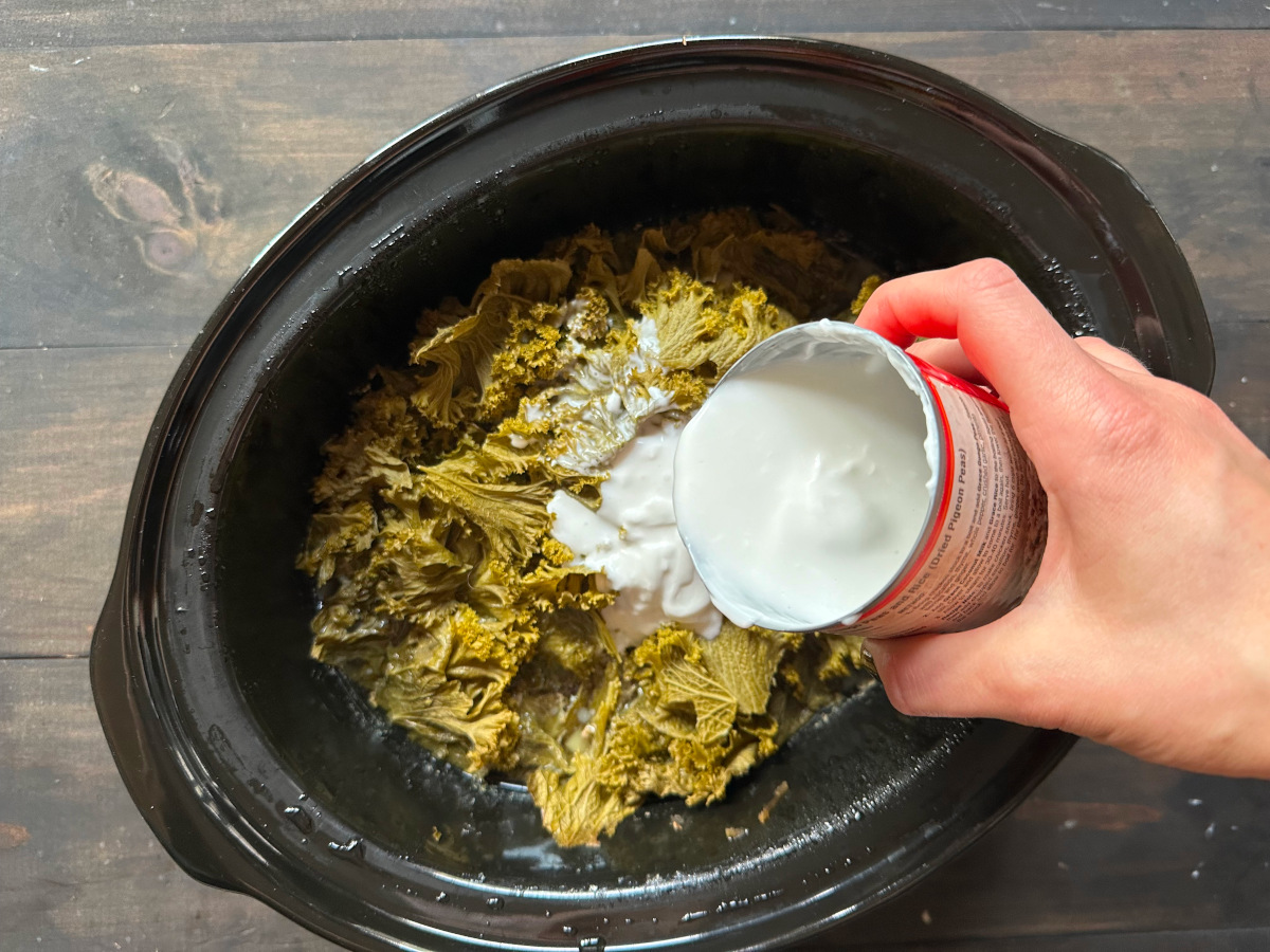 The coconut milk being added to the cooked soup.