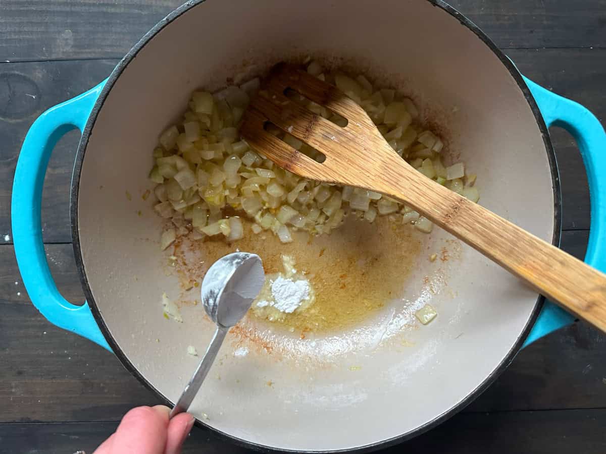 The flour being added to the pan of onions and garlic.