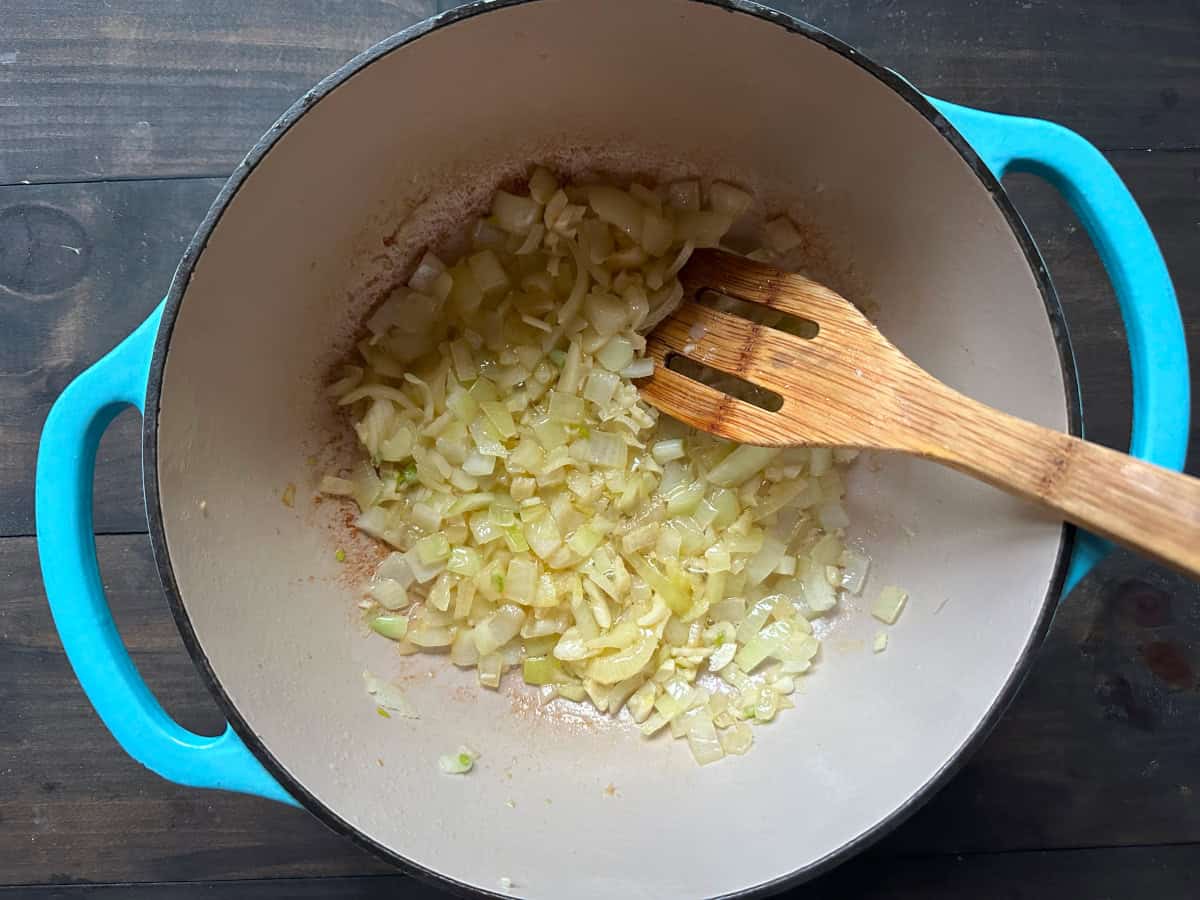 The onion and garlic sautéing in the dutch oven with the spoon.