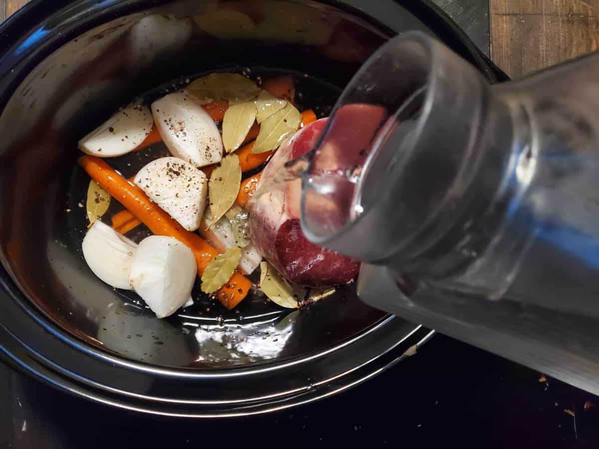 Water being poured onto the veggies and bones.