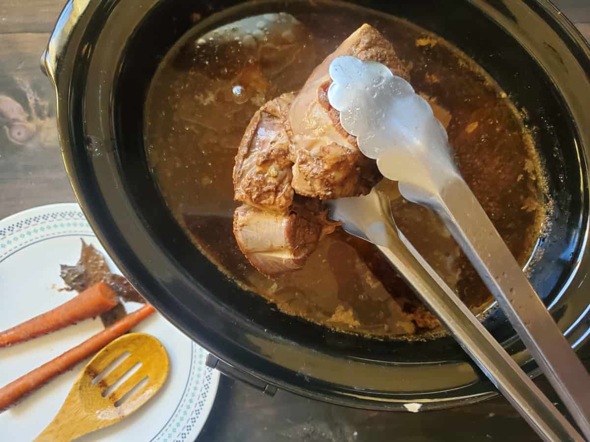 Tongs removing the bones from the broth.