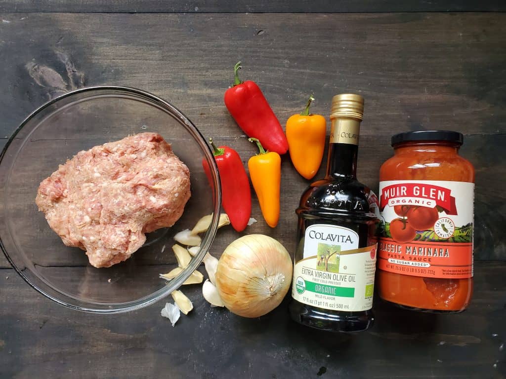 A picture of the ingredients needed for this Italian Sausage Meal. From left to right is ground Italian Sausage, peppes, garlic, an onion, olive oil, and marinara sauce.