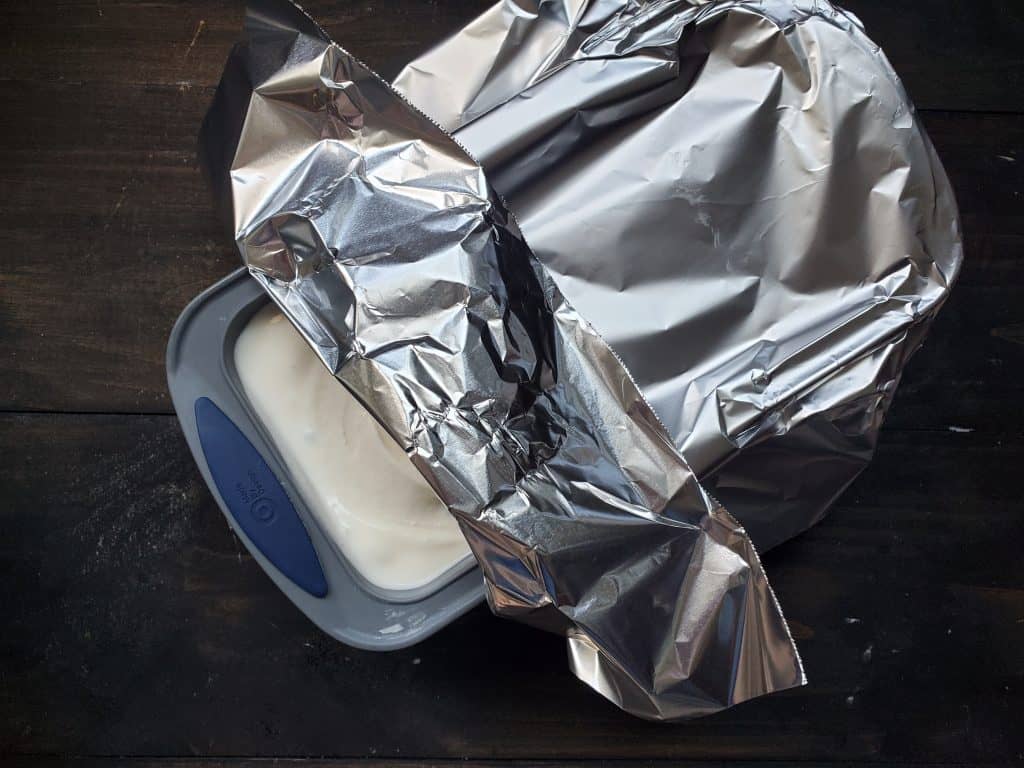 The ice cream is in a freezer safe container, and partially wrapped with foil.