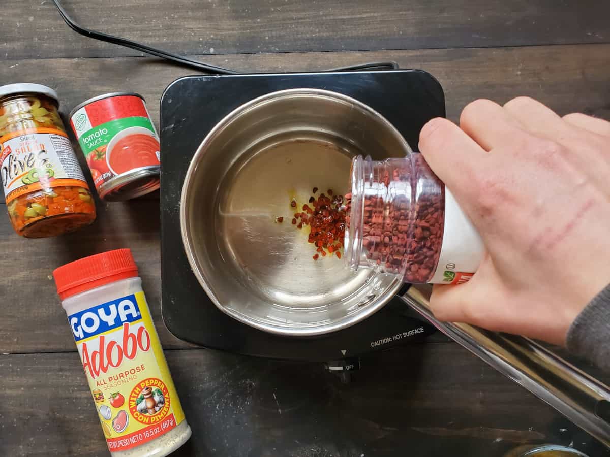 The seeds being added to a saucepan with ingredients on the side.