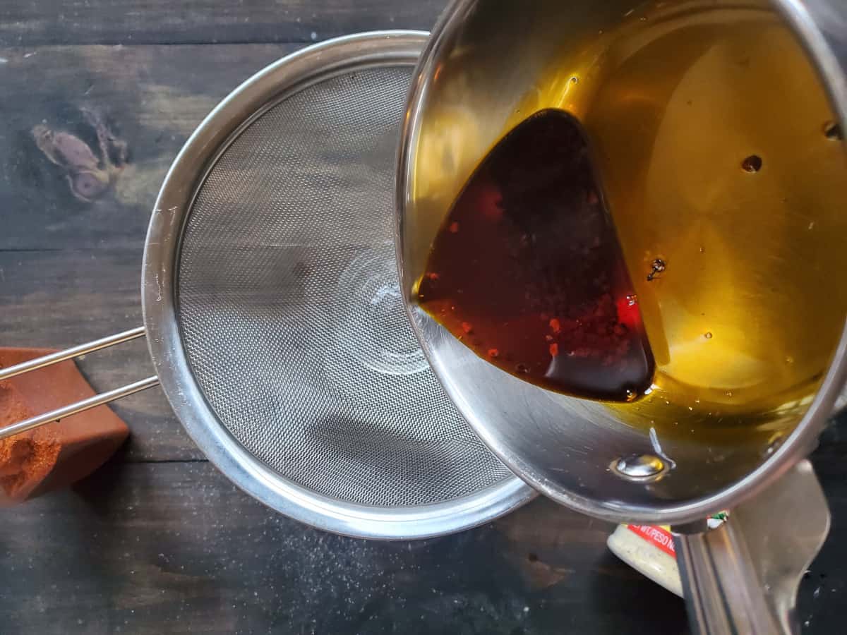 The oil and seeds being poured into a strainer.