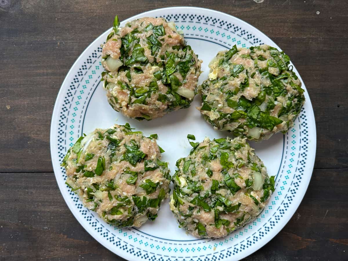 The raw burger patties on a plate.