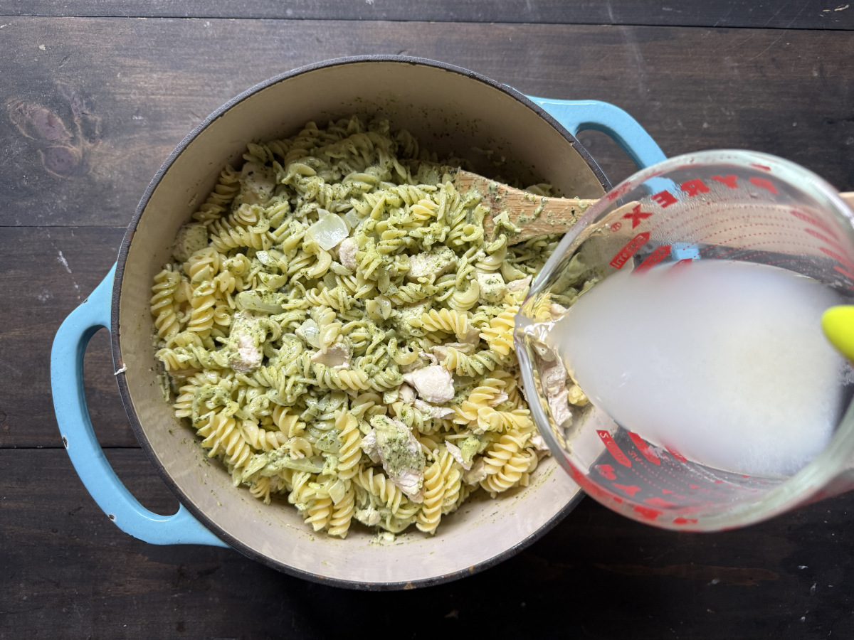 The pasta cooking water being poured into the pasta dish.