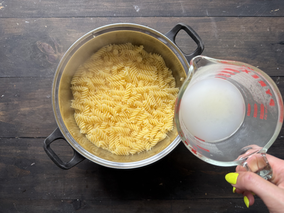 A dish with the drained pasta and a cup with the reserved pasta cooking water.