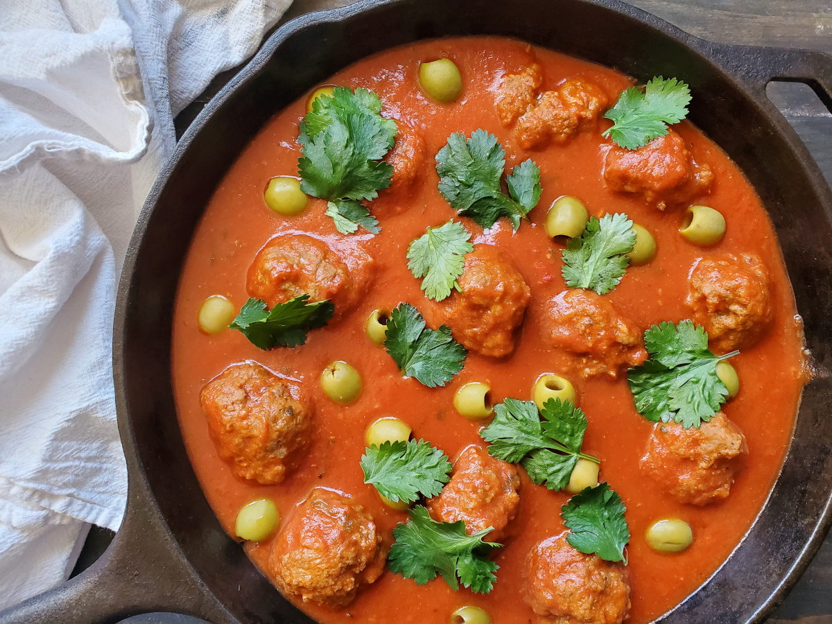 Puerto Rican Meatballs in a cast iron skillet garnished with cilantro.