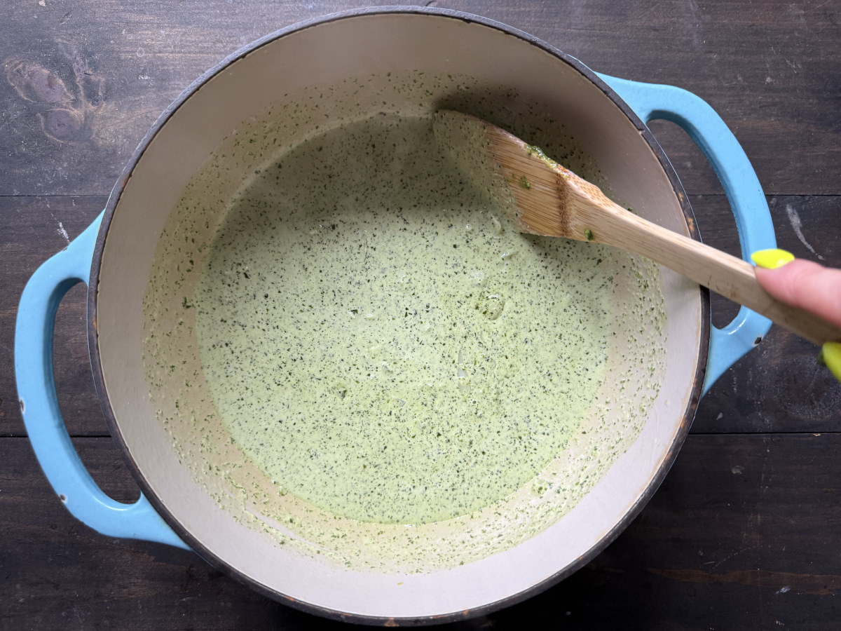 The heavy cream and pesto being stirred into the onion mixture.