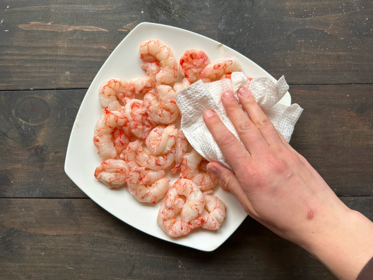 Patting dry the shrimp on a plate.