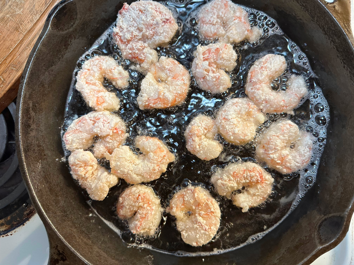 The shrimp being fried in a cast iron skillet.