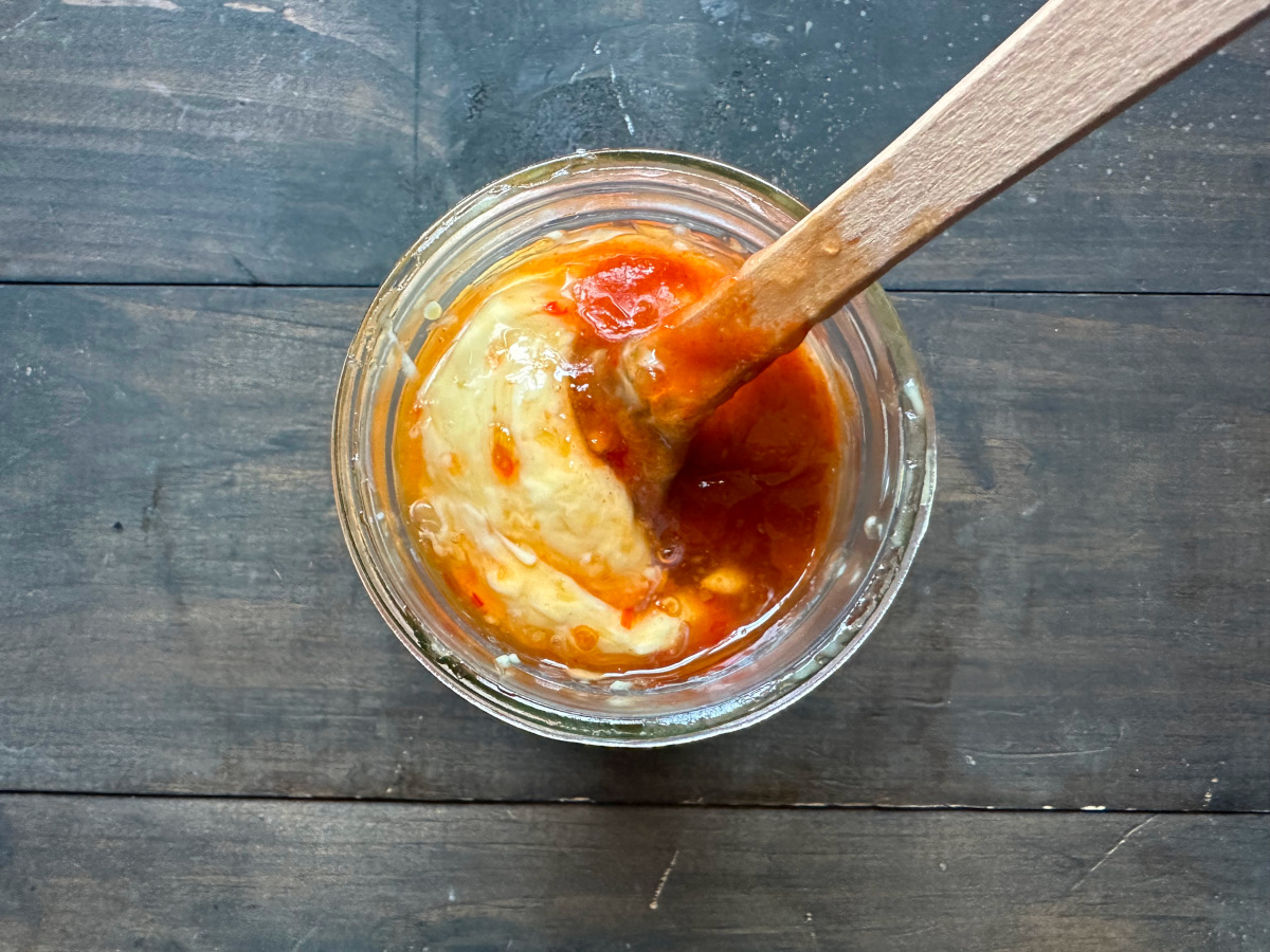 The ingredients for the sauce in a jar with a rubber spatula.