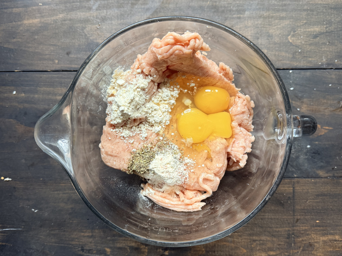 The meatball ingredients in a glass mixing bowl.