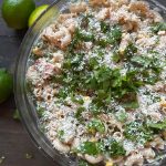 A bowl of Mexican Street Corn Pasta Salad with limes.