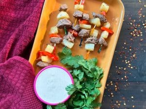 A dish of garlic butter steak bites with sauce and greens.