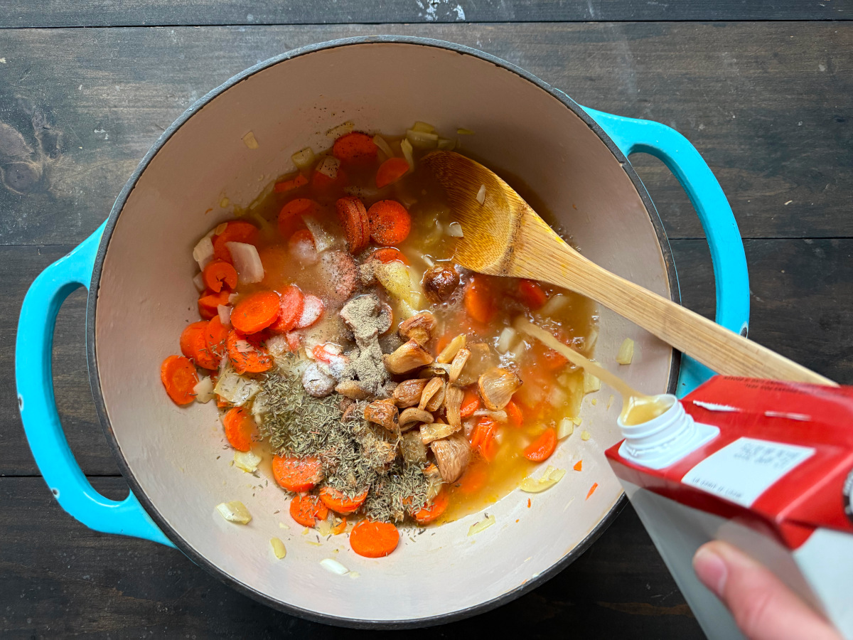 Broth being added into the pot of veggies.